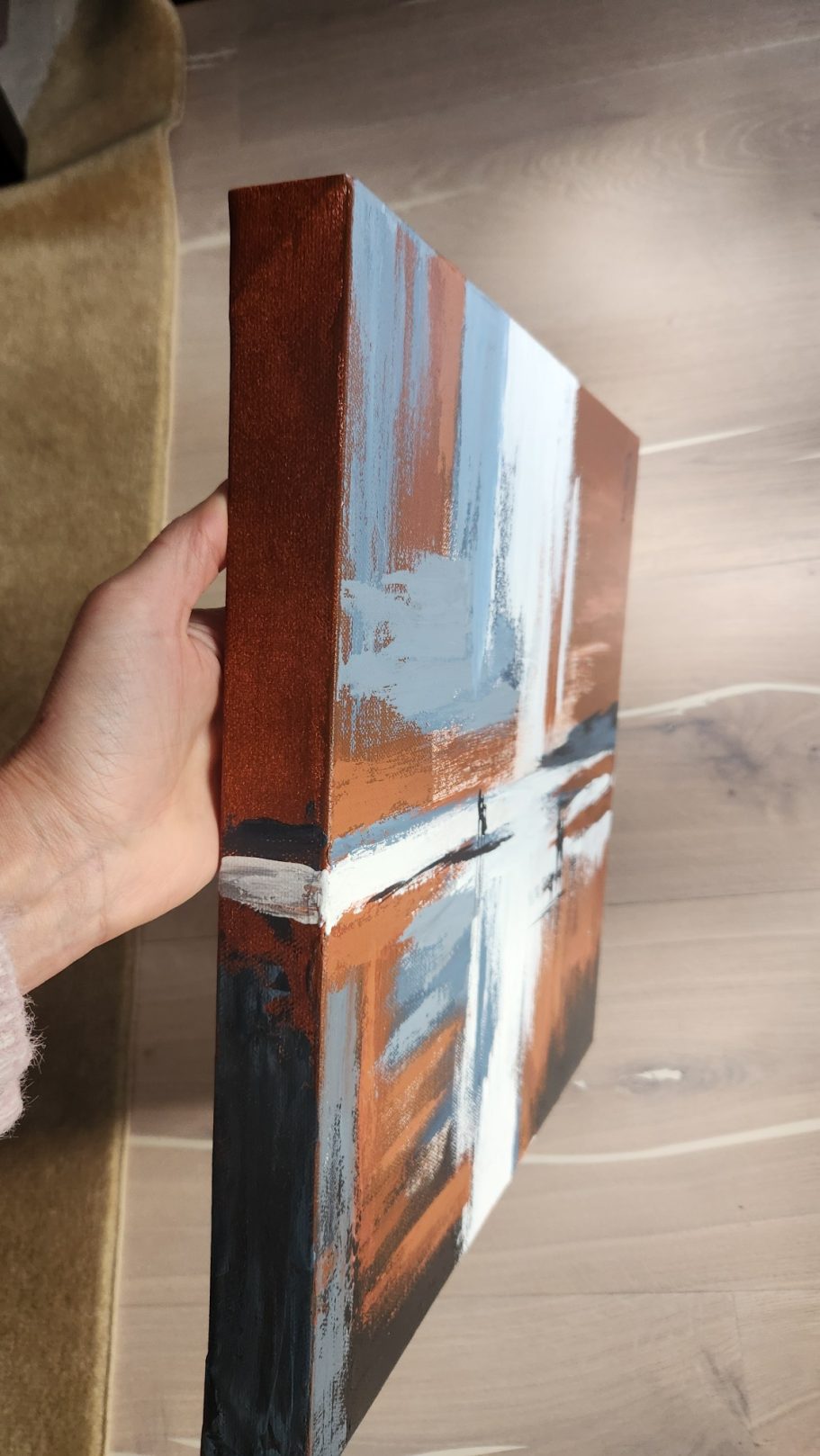 Abstraktes Gemälde mit Holz- und Blautönen, von der Seite gehalten.